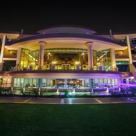 אבו דאבי Al Raha Beach Resort & Spa מראה חיצוני תמונה The photo shows a modern architectural building illuminated at night. The structure has a large central entrance with multiple glass windows, flanked by symmetrical columns. The exterior features a combination of sleek lines and curves, with lighting
