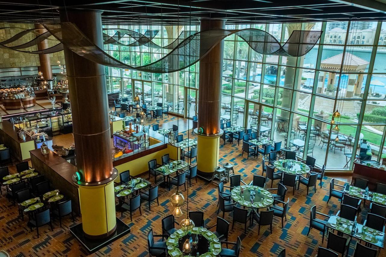 אבו דאבי Al Raha Beach Resort & Spa מראה חיצוני תמונה The photo shows the interior of a restaurant with a modern design. It features large windows allowing natural light to flood the space, creating an inviting atmosphere. The dining area is furnished with round tables covered with green tablecloths and