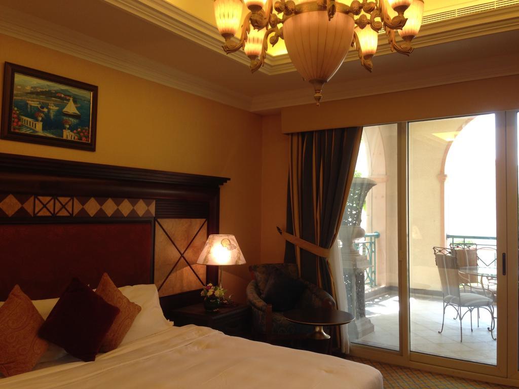 אבו דאבי Al Raha Beach Resort & Spa מראה חיצוני תמונה The photo shows the interior of a hotel room. The room features a large bed with decorative cushions and a wooden headboard. There's a bedside lamp emitting a warm light, and a painting is hung on the wall above the bed. To the right, there's a windo