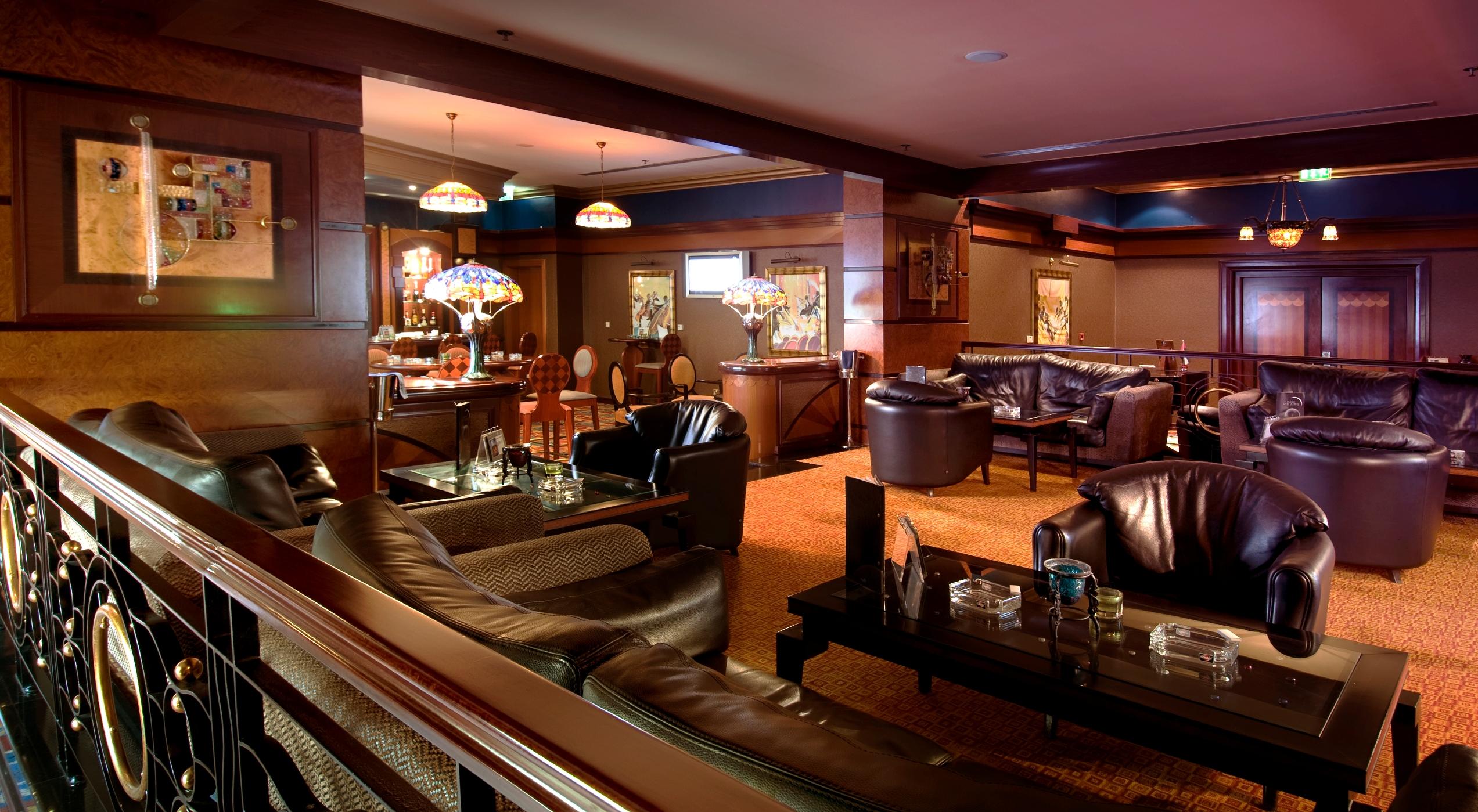 אבו דאבי Al Raha Beach Resort & Spa מראה פנימי תמונה The photo depicts a stylish lounge area featuring comfortable seating and an inviting atmosphere. There are several plush leather armchairs and sofas arranged around low tables. The space is well-lit, with stained glass lamps providing warm light. Th