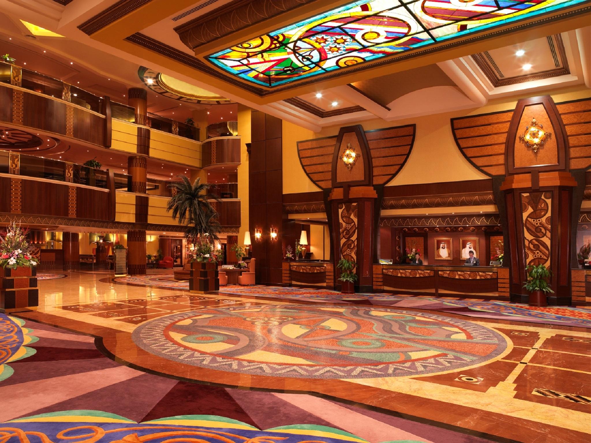 אבו דאבי Al Raha Beach Resort & Spa מראה פנימי תמונה The photo depicts an elegantly designed hotel lobby. It features a grand ceiling with intricate stained glass and decorative patterns. The floor is adorned with colorful, ornate designs, including circular patterns. The lobby is spacious, with wooden