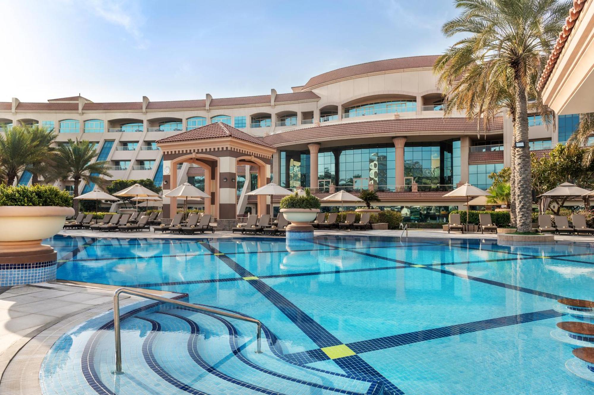 אבו דאבי Al Raha Beach Resort & Spa מראה חיצוני תמונה The photo shows a luxurious resort with a large swimming pool in the foreground. The pool has a clean, blue surface and features lounge chairs on the surrounding deck. In the background, there is a stylish and modern hotel building with multiple stor