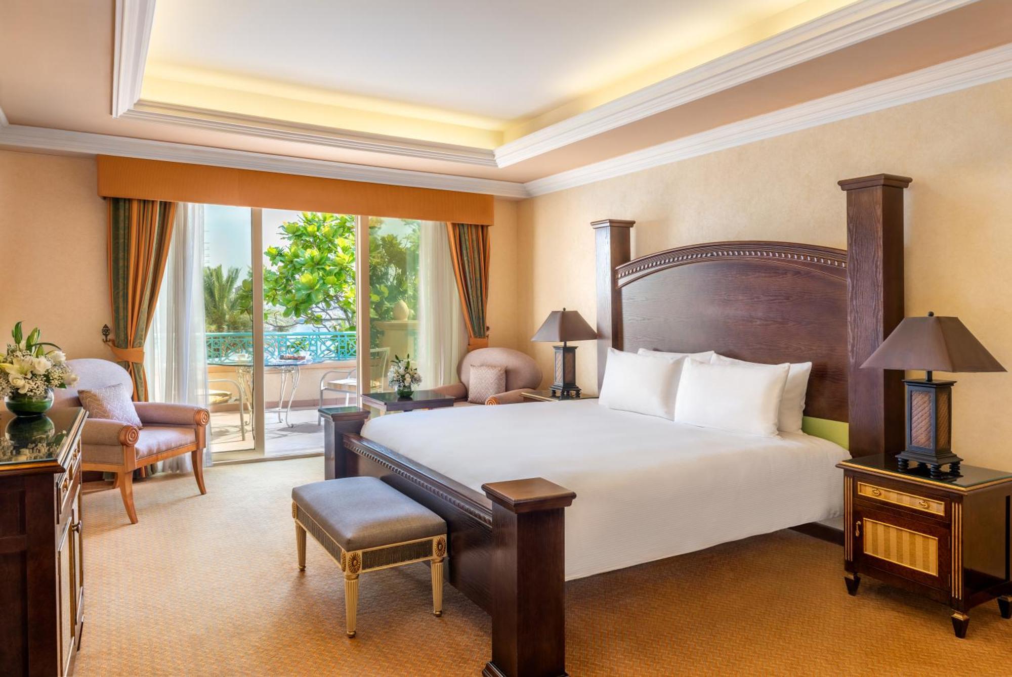 אבו דאבי Al Raha Beach Resort & Spa מראה חיצוני תמונה The photo shows a well-appointed hotel bedroom. It features a large bed with white bedding, flanked by bedside tables with lamps. The room has light-colored walls and a warm-toned carpet. There is a comfortable seating area with a chair and a small t