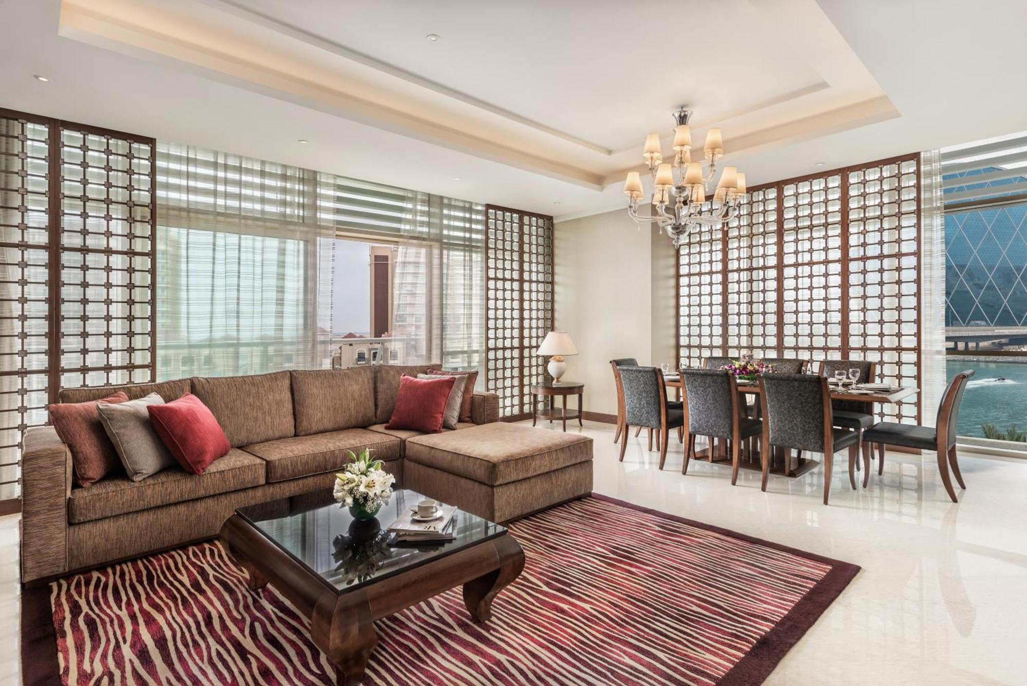 אבו דאבי Al Raha Beach Resort & Spa מראה חיצוני תמונה The photo shows a stylish and modern living space. On one side, there is a comfortable sectional sofa in a brown upholstery, accented with red and gray cushions. In front of the sofa, there is a glossy black coffee table adorned with a small floral a